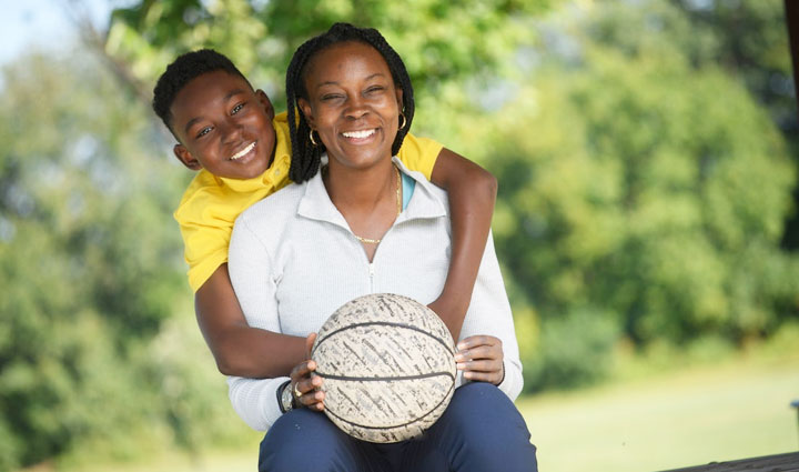 Wounded Warrior Danielle Green, seated, holds a basketball and smiles with her 10-year-old son.