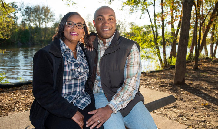 Wounded warrior Sean Sanders and his wife sit outside on a fall day smiling and wearing plaid shirts and vests.