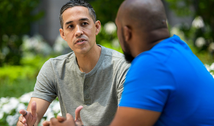 Wounded warrior Sergio Alfaro sits on a park bench talking to a fellow warrior.