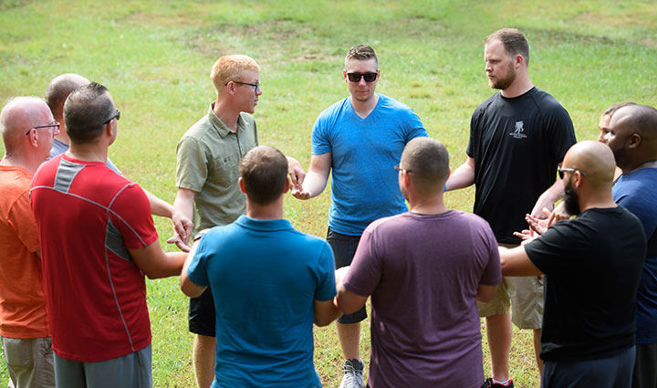 A group of warriors stand in a circle while holding hands.