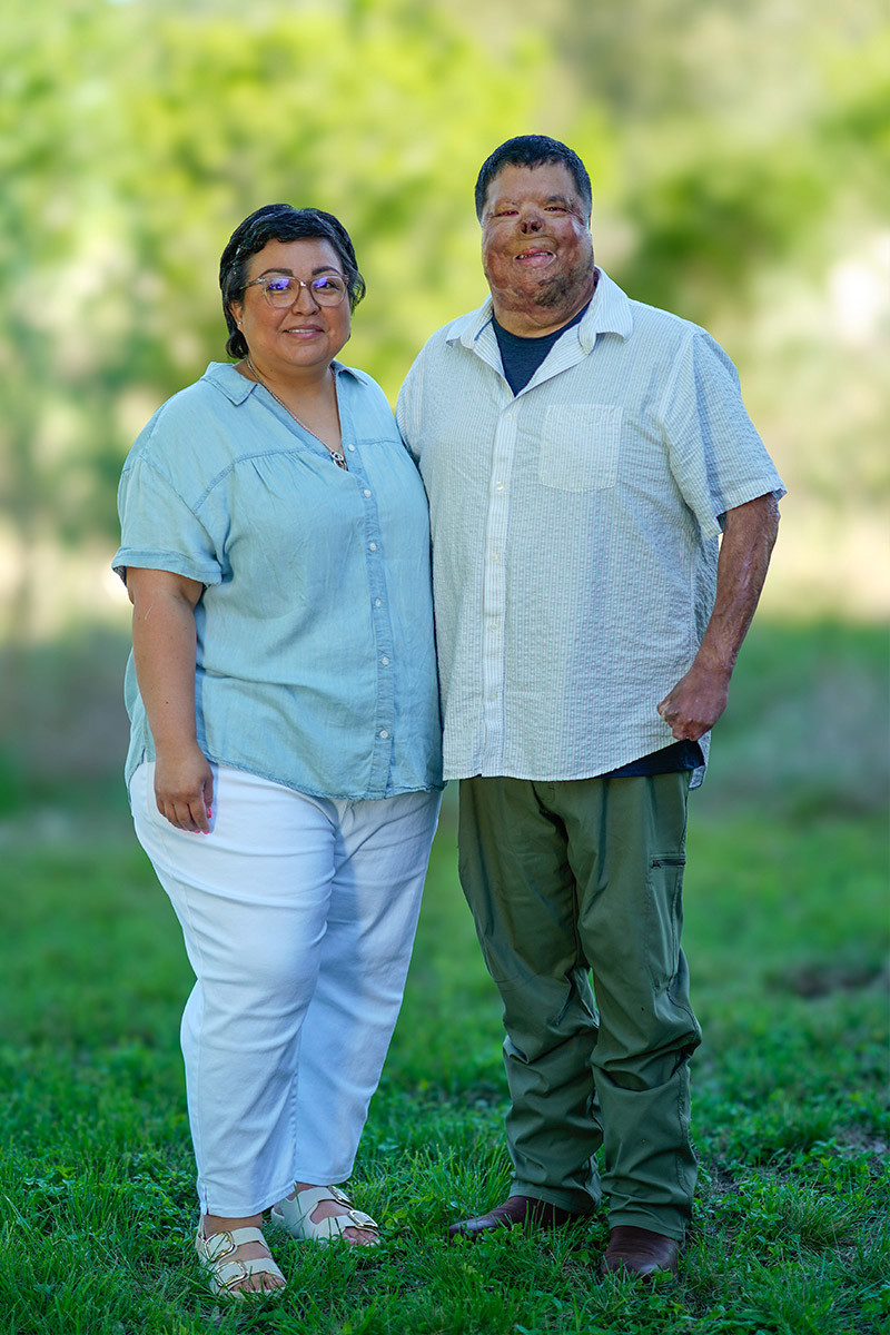 Wounded warrior Anthony Villareal stands smiling next to his wife in a patch of grass.
