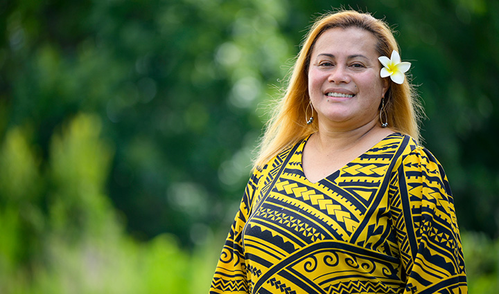 Wounded warrior Pele Hunkin stands outside and smiles at the camera with a plumeria flower tucked in her hair.