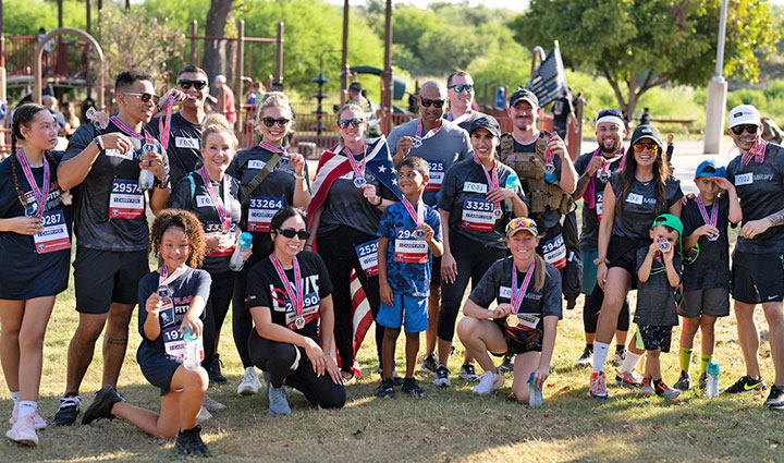 Twenty participants of the Carry Forward 5K gather together, proudly showing off their medals for a group photo.