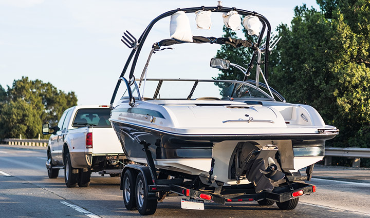 A pickup truck towing a boat on the interstate.