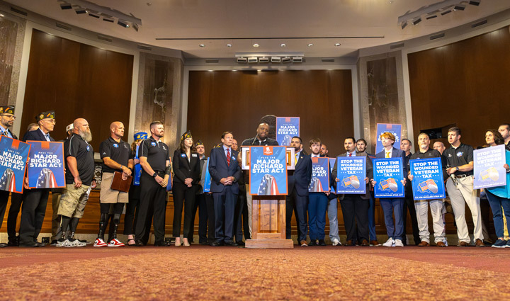 A group of veterans, wounded warriors, and lawmakers stands in solidarity during a Capitol Hill press conference, holding signs in support of the Major Richard Star Act and calling to end the “Wounded Veteran Tax.” 