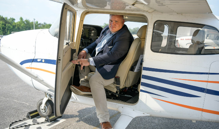 Wounded warrior Jake Norotsky climbs out of a small propeller airplane cockpit.