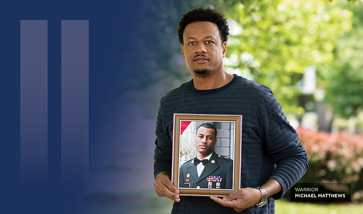 Warrior Michael Matthews stands outdoors holding a framed military portrait of himself, with a teal background overlay and vertical graphic bars.