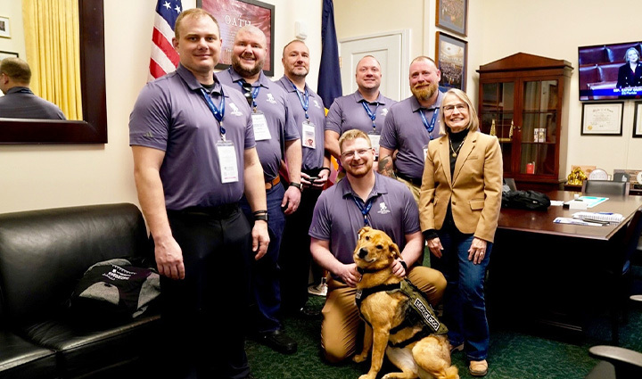 A group of warriors and a service dog inside a congressional office. 